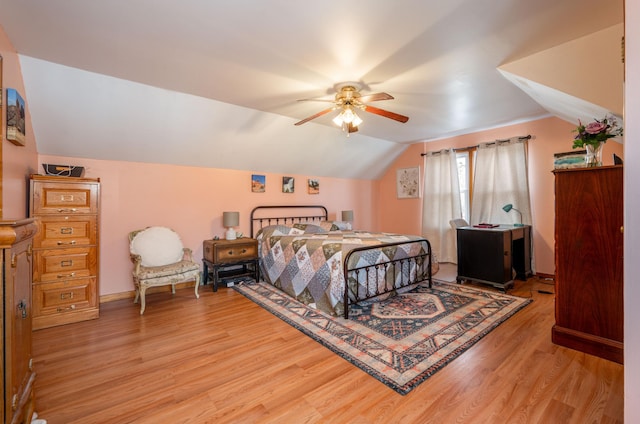 bedroom featuring light wood finished floors, baseboards, lofted ceiling, and a ceiling fan