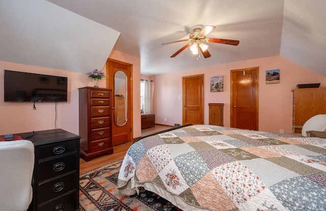 bedroom featuring a ceiling fan, lofted ceiling, and light wood-style floors