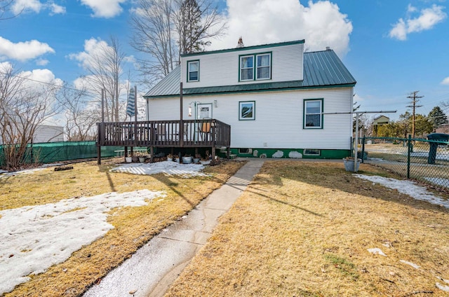 back of house featuring metal roof, a lawn, a wooden deck, and fence