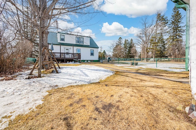 back of property featuring metal roof, a wooden deck, and fence