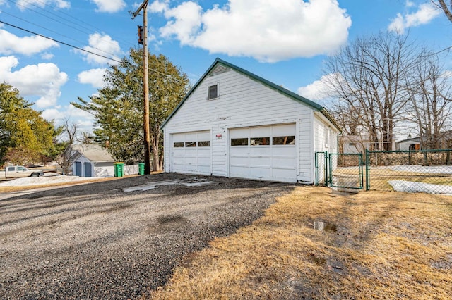 view of property exterior featuring an outdoor structure, fence, a garage, and a gate