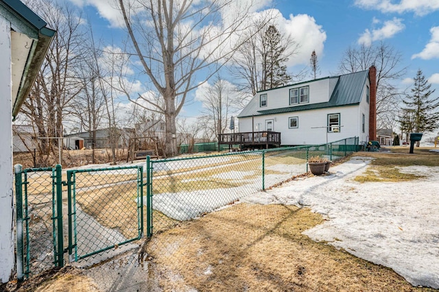 rear view of property with metal roof, fence, a chimney, and a gate