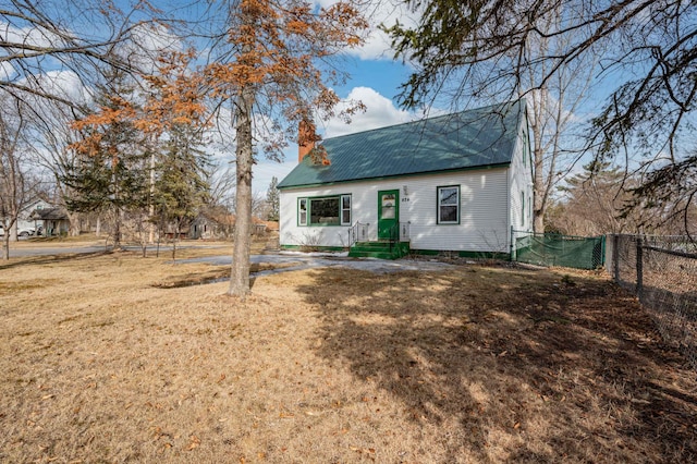 view of front facade with a front yard, fence, a chimney, and metal roof