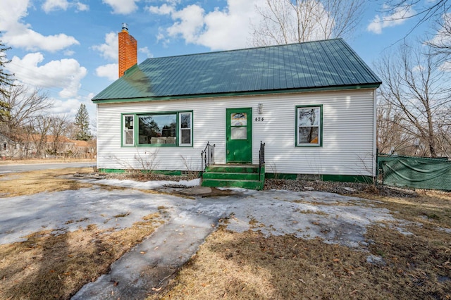 view of front of property featuring a chimney and metal roof