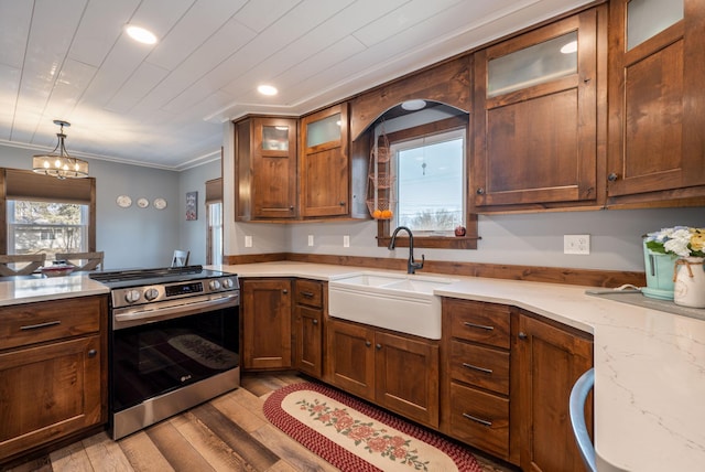 kitchen featuring a chandelier, ornamental molding, stainless steel range with electric stovetop, light wood-style floors, and a sink