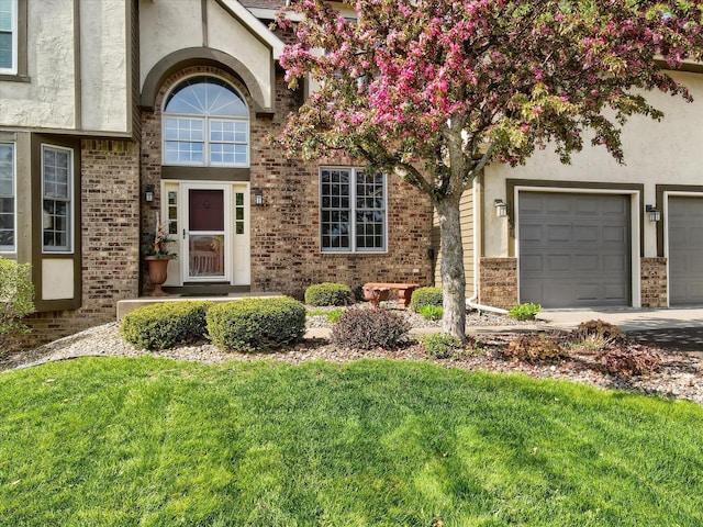 entrance to property featuring a yard, brick siding, and stucco siding