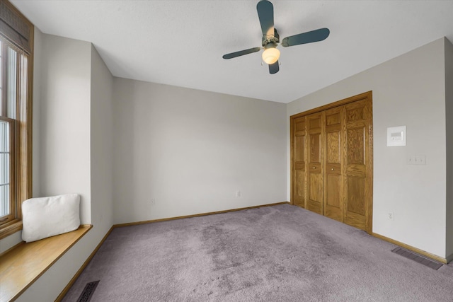 unfurnished bedroom with visible vents, a closet, carpet, baseboards, and ceiling fan