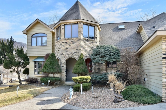 view of front of home with brick siding and roof with shingles