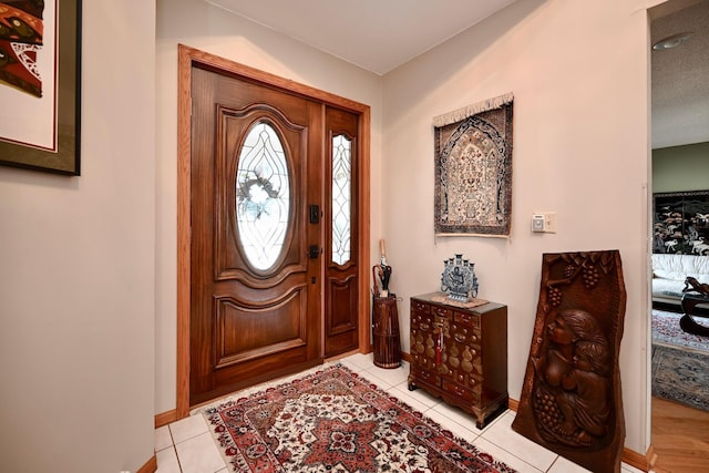 foyer entrance with light tile patterned floors and baseboards