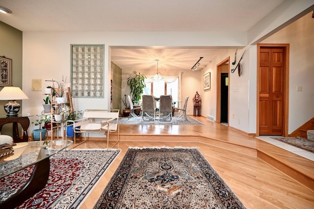 living room with visible vents, baseboards, an inviting chandelier, and wood finished floors