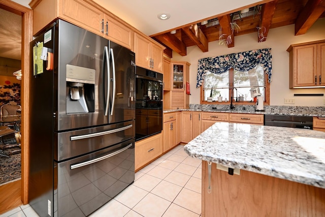 kitchen featuring light stone counters, light tile patterned floors, beam ceiling, a sink, and stainless steel fridge