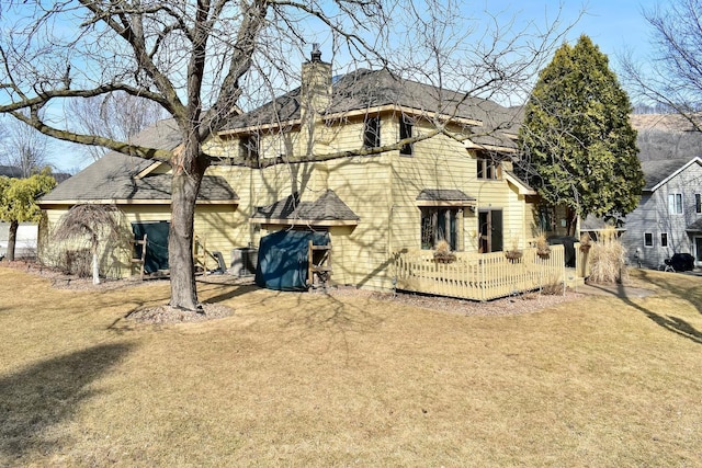 rear view of property featuring a yard and a chimney