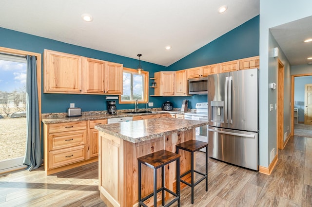 kitchen featuring light brown cabinetry, a sink, a center island, stainless steel appliances, and light wood-style floors