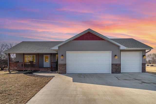 ranch-style house with a porch, concrete driveway, a garage, and stone siding