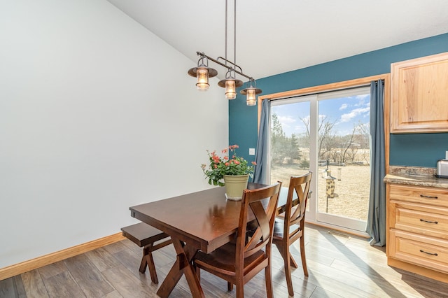 dining area featuring baseboards, light wood-type flooring, and lofted ceiling