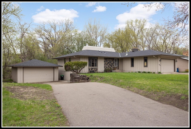 view of front of property featuring a detached garage, a front lawn, a chimney, and board and batten siding