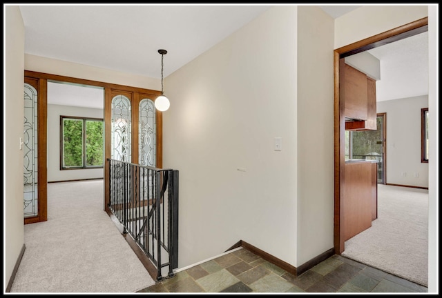 hallway featuring carpet floors, baseboards, and an upstairs landing