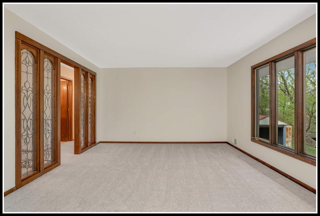 unfurnished room with light carpet and baseboards