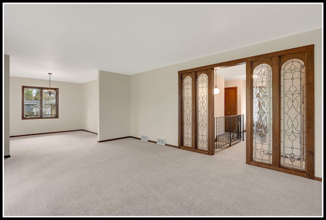 carpeted empty room with an inviting chandelier, baseboards, and visible vents