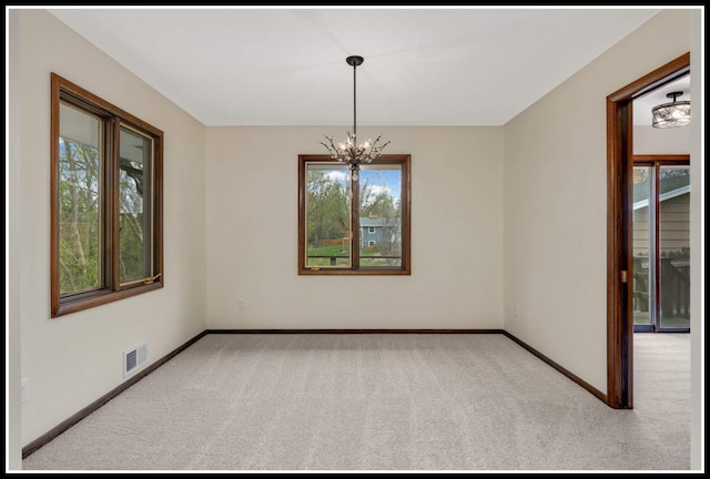 empty room with an inviting chandelier, carpet flooring, baseboards, and visible vents