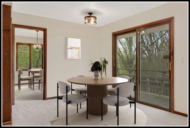 dining room with an inviting chandelier, light carpet, and baseboards