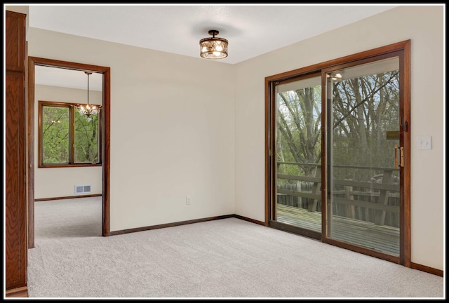 carpeted empty room featuring baseboards, a chandelier, and visible vents