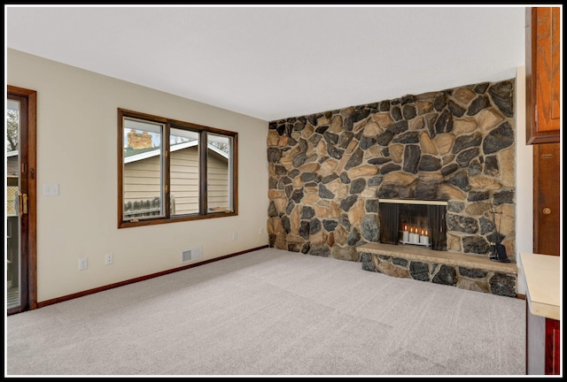unfurnished living room with plenty of natural light, visible vents, a fireplace, and carpet floors
