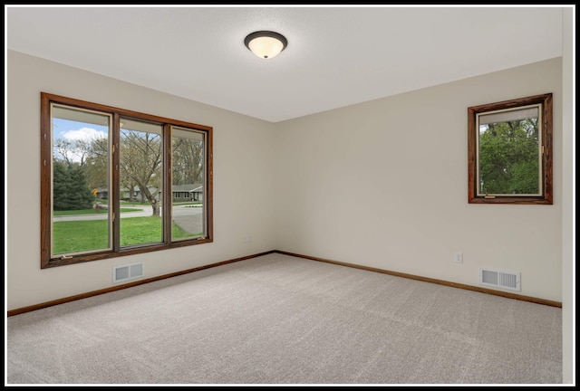 carpeted empty room featuring baseboards, a wealth of natural light, and visible vents