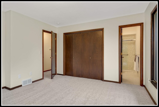 unfurnished bedroom with carpet, a closet, visible vents, baseboards, and ensuite bath