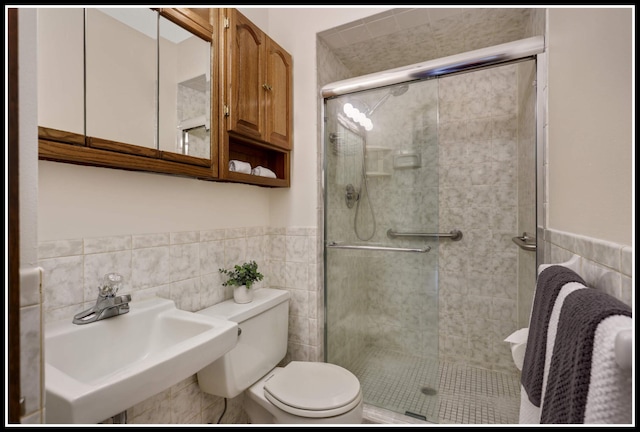bathroom with tile walls, toilet, and a stall shower