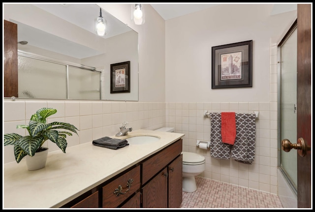 bathroom with toilet, tile walls, vanity, tile patterned floors, and wainscoting