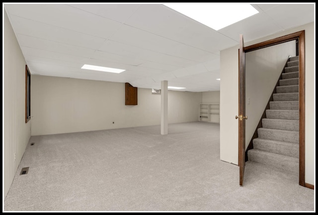 finished below grade area featuring carpet flooring, visible vents, and stairs