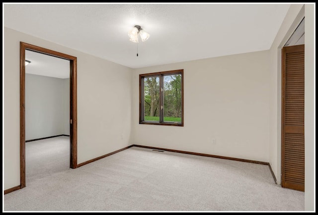 empty room featuring light carpet, baseboards, and visible vents