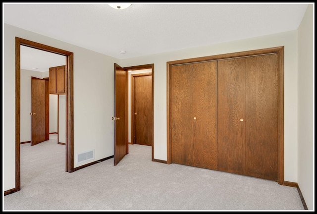 unfurnished bedroom featuring baseboards, a closet, visible vents, and carpet