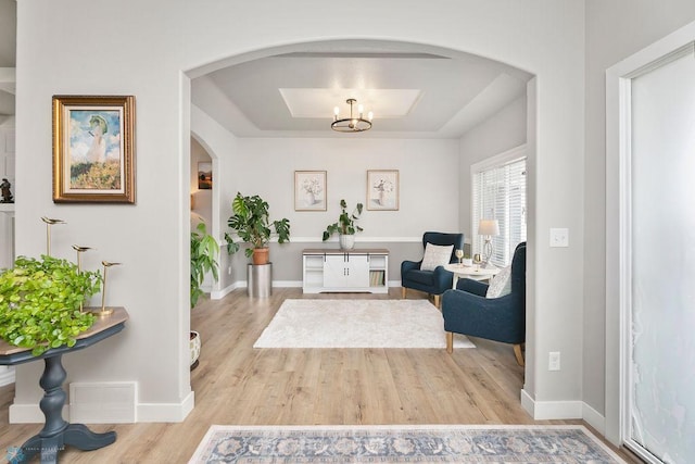 living area with wood finished floors, visible vents, arched walkways, and baseboards