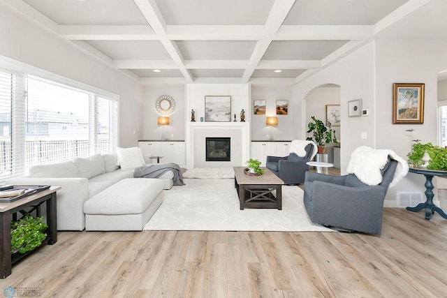 living room with arched walkways, beamed ceiling, coffered ceiling, and wood finished floors