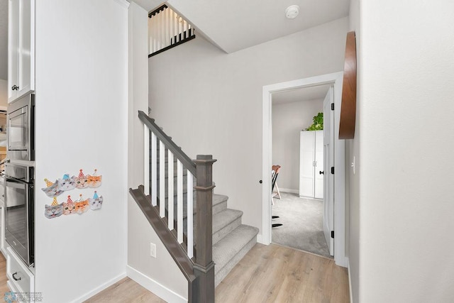 stairs with wood finished floors and baseboards