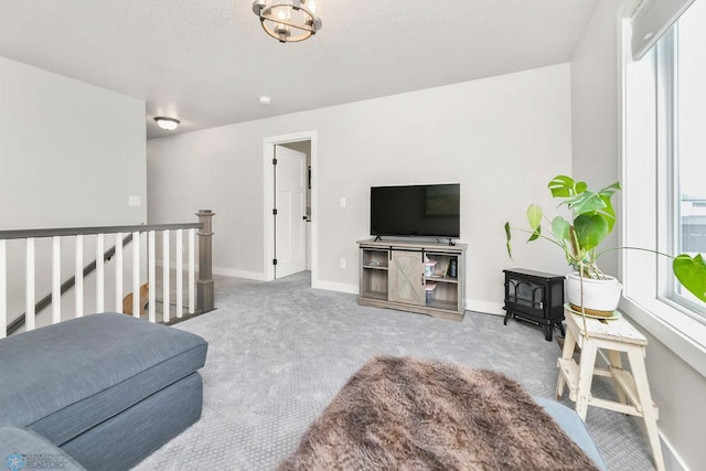 carpeted living room featuring a wood stove and baseboards