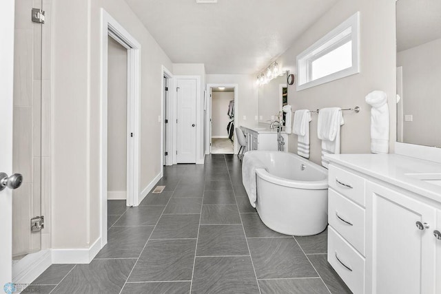 full bathroom featuring tile patterned floors, visible vents, baseboards, a freestanding bath, and vanity