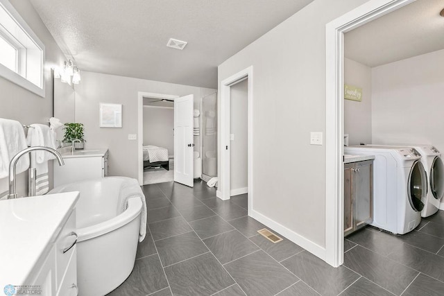 bathroom with ensuite bath, visible vents, vanity, and separate washer and dryer