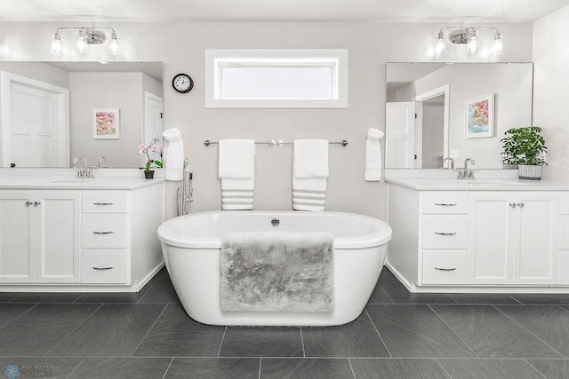 full bath featuring a freestanding tub, two vanities, and a sink