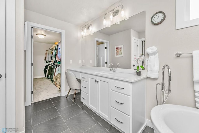 bathroom featuring baseboards, a spacious closet, and vanity