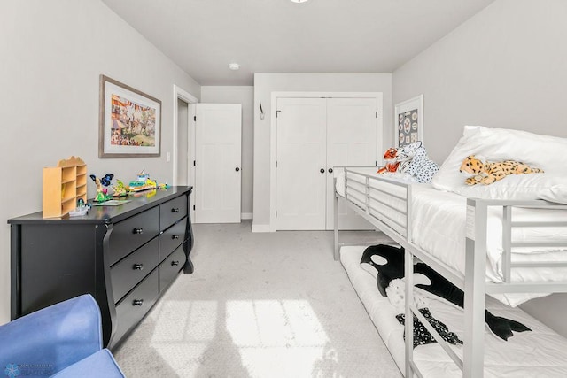 bedroom with a closet, baseboards, and light colored carpet