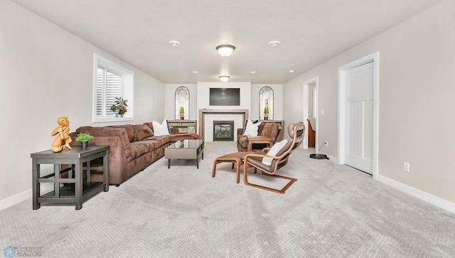 living area featuring a glass covered fireplace, carpet, and baseboards