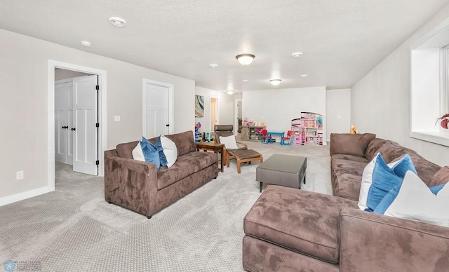 living area with a textured ceiling, baseboards, and carpet