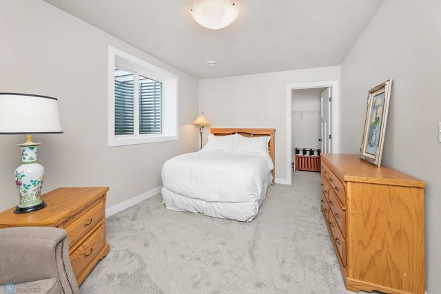 bedroom featuring baseboards, light carpet, a closet, and a spacious closet