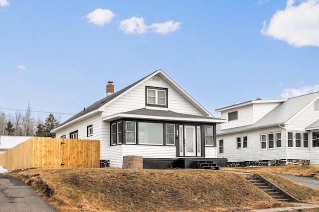 bungalow-style home featuring fence, roof with shingles, and a chimney