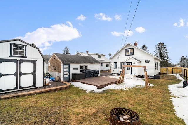 rear view of property featuring a yard, a deck, a storage shed, and an outdoor structure