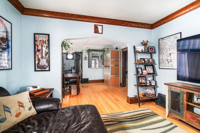 living room featuring baseboards, arched walkways, wood finished floors, and ornamental molding