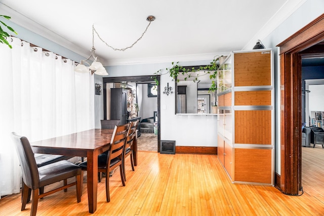 dining room featuring visible vents, wood-type flooring, baseboards, and ornamental molding